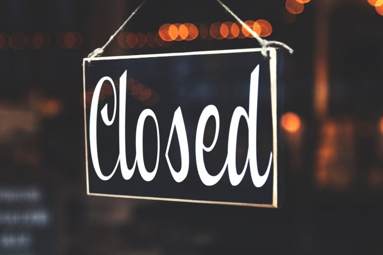 A closed sign stands out in front of a bokeh background