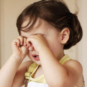 A child rubs her eyes