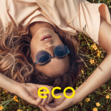 ECO frames available at Spectrum Optical: A girl lays in a field of butterciups wearing blue tinted sunglasses