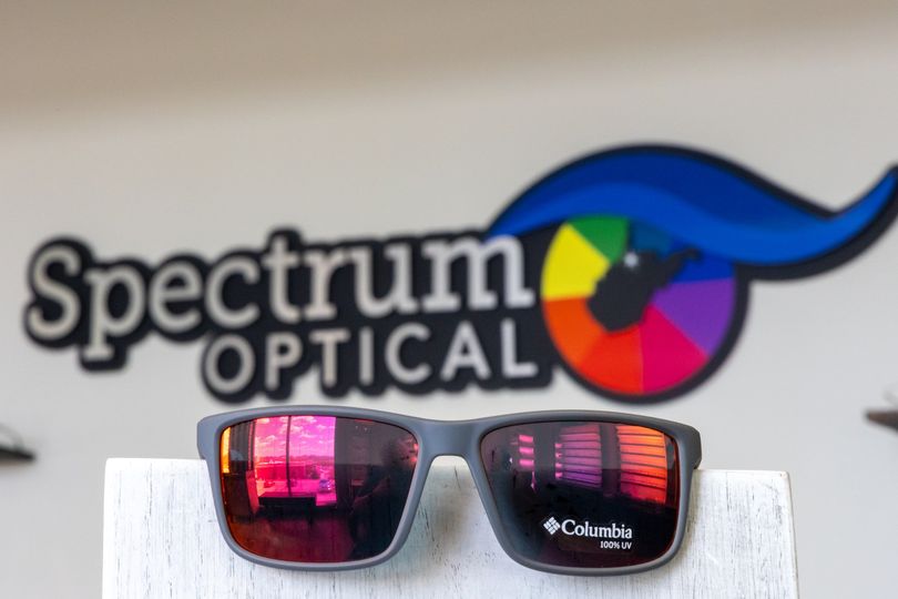 Reflective Columbia sunglasses in front of the Spectrum Optical logo
